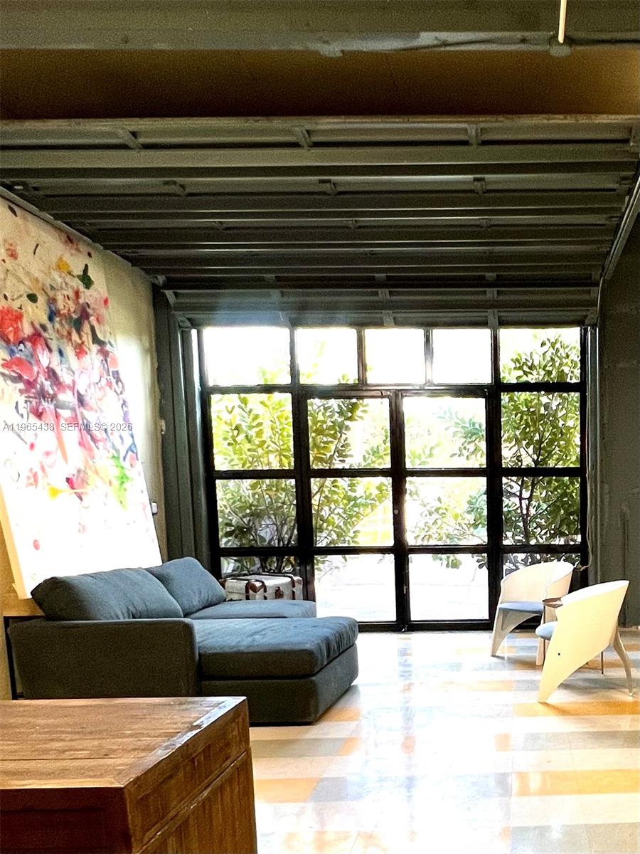 A living room features a grey sectional sofa, modern chairs, and large industrial-style windows — 3257 NW 7 Ave Cir # A, Miami FL 33127, MIAMI, FL