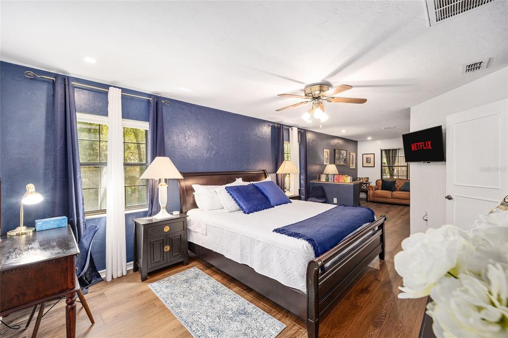 A bedroom features a dark blue accent wall, a wooden bed frame, and wood flooring — 9800 SW 190TH TERRACE ROAD, DUNNELLON, FL