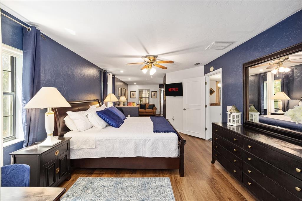 A bedroom features dark blue walls, a king-sized bed, wood flooring, and a large dresser — 9800 SW 190TH TERRACE ROAD, DUNNELLON, FL