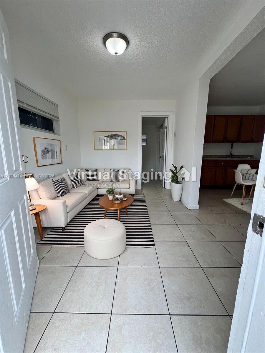 A living room with tile floors and virtual furniture staging leads into a kitchen area — 1754 NW 45th St # 1754, Miami FL 33142, MIAMI, FL