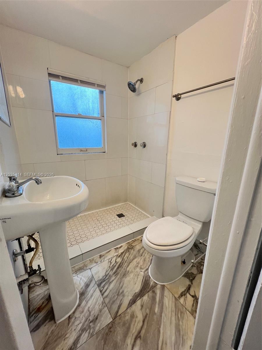 A small bathroom features a pedestal sink, a toilet, and a tiled walk-in shower — 1754 NW 45th St # 1754, Miami FL 33142, MIAMI, FL