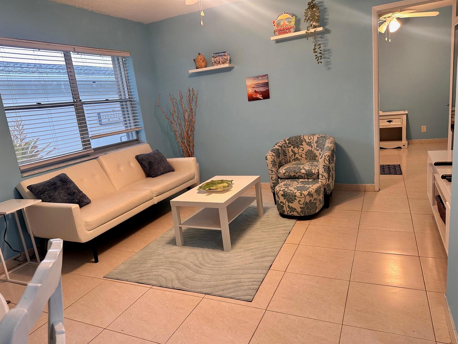 A light blue living room features a white sofa, patterned armchair, and a coffee table — 3240 NE 16th Street # 7, Pompano Beach FL 33062, POMPANO BEACH, FL