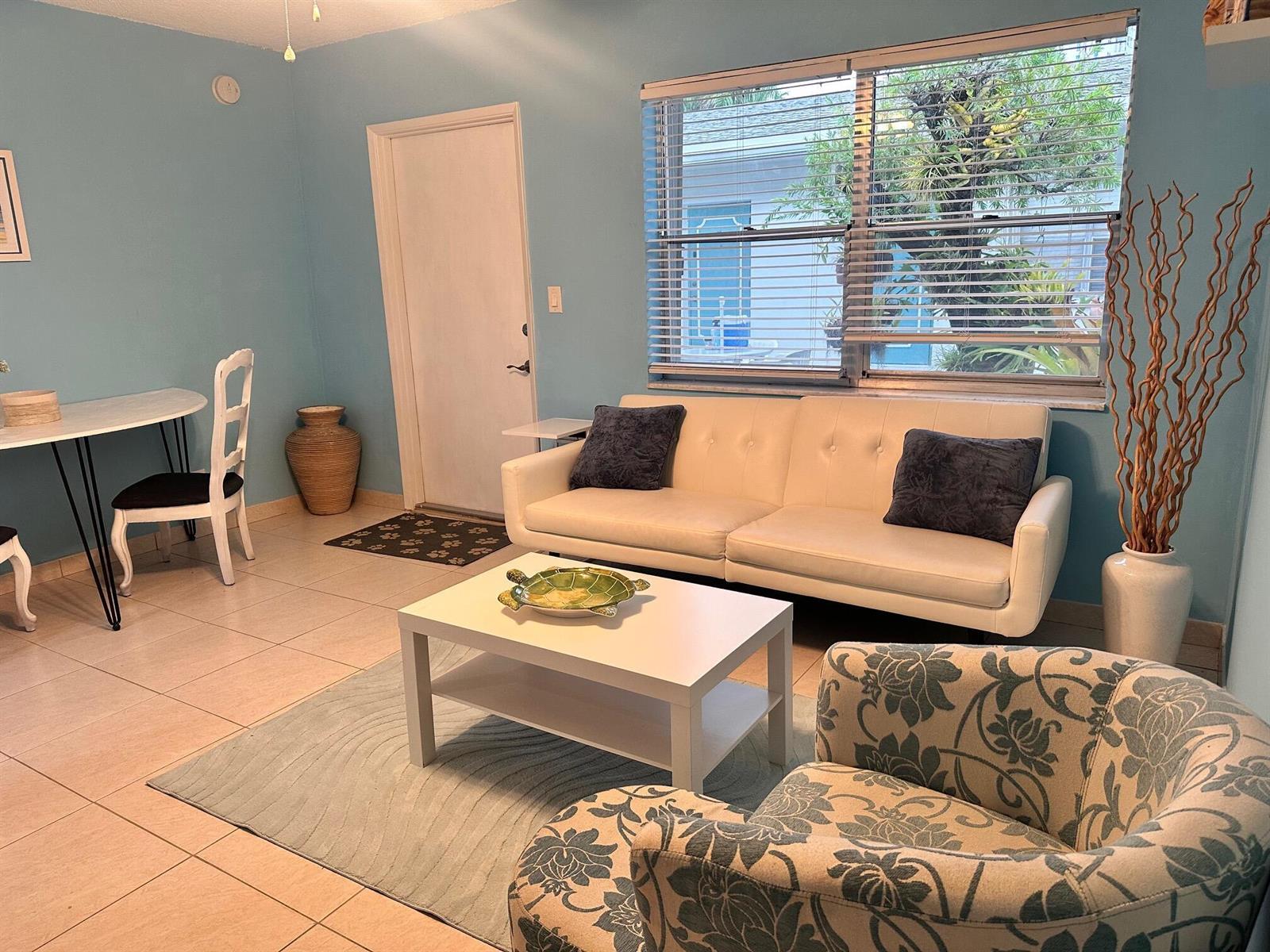 A living room with light blue walls, a white sofa, a coffee table, and tile flooring — 3240 NE 16th Street # 7, Pompano Beach FL 33062, POMPANO BEACH, FL