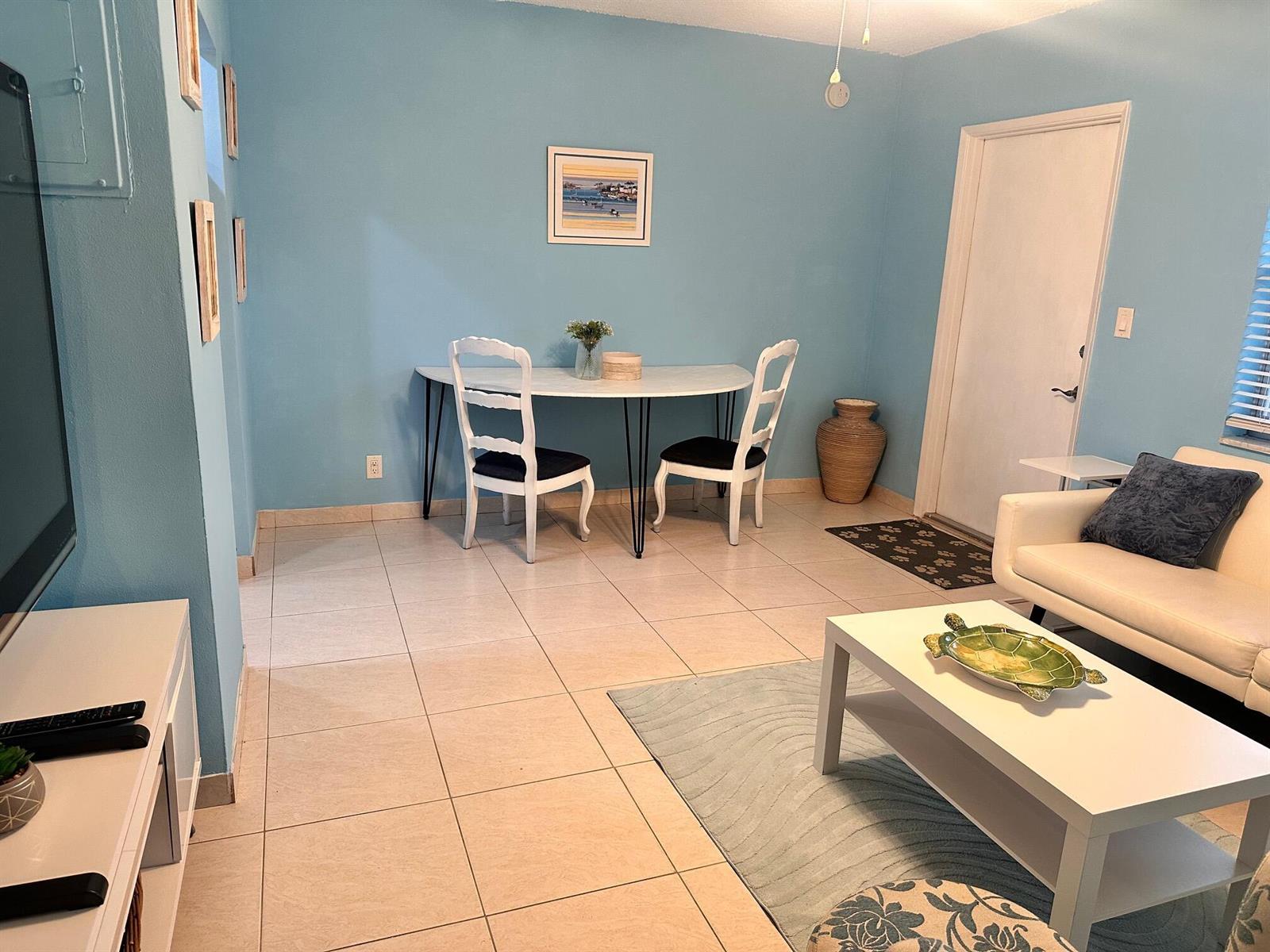 A living room with light blue walls, tile flooring, a dining set, and a white sofa — 3240 NE 16th Street # 7, Pompano Beach FL 33062, POMPANO BEACH, FL