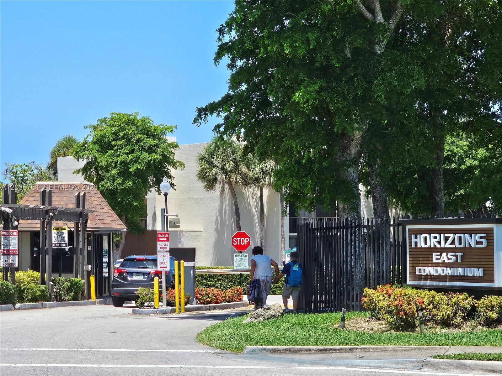 The entrance to Horizons East Condominium features a security gate, signage, and a landscaped driveway — 8075 SW 107th Ave # 114, Miami FL 33173, MIAMI, FL
