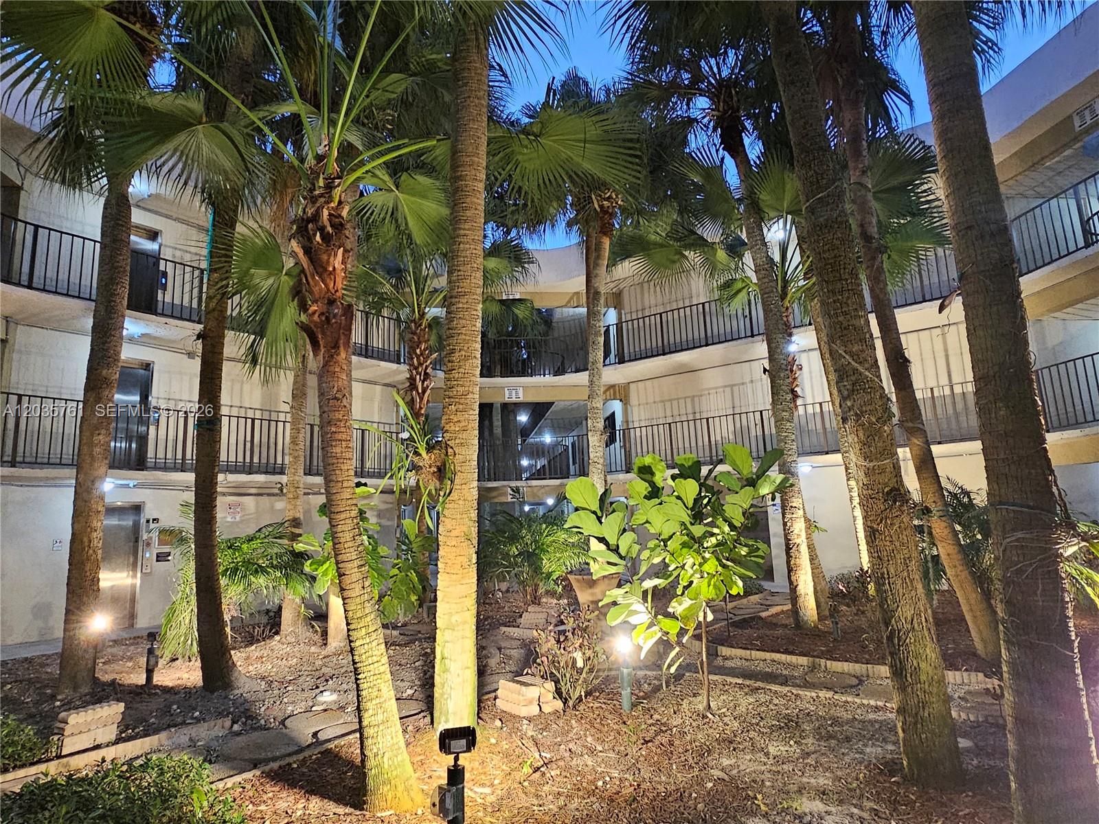 A courtyard with palm trees and multi-story balconies at dusk — 8075 SW 107th Ave # 114, Miami FL 33173, MIAMI, FL