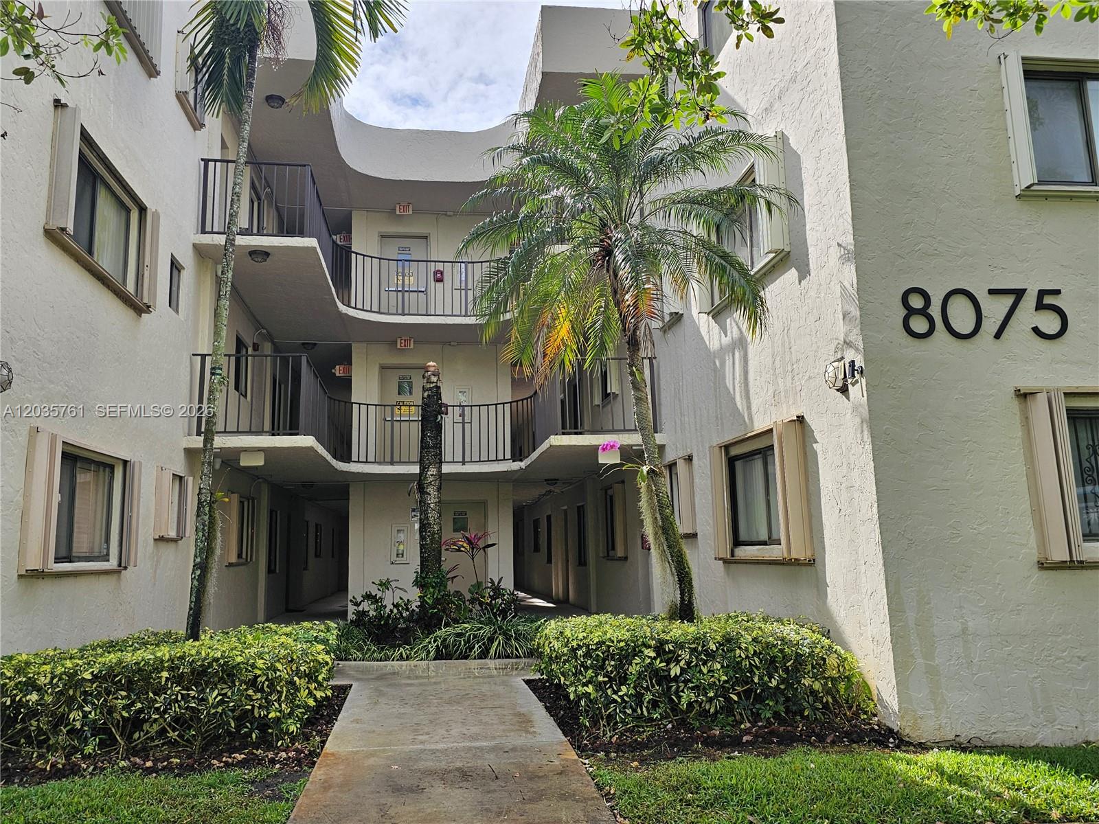 A three-story apartment building exterior features balconies, palm trees, and a central walkway — 8075 SW 107th Ave # 114, Miami FL 33173, MIAMI, FL