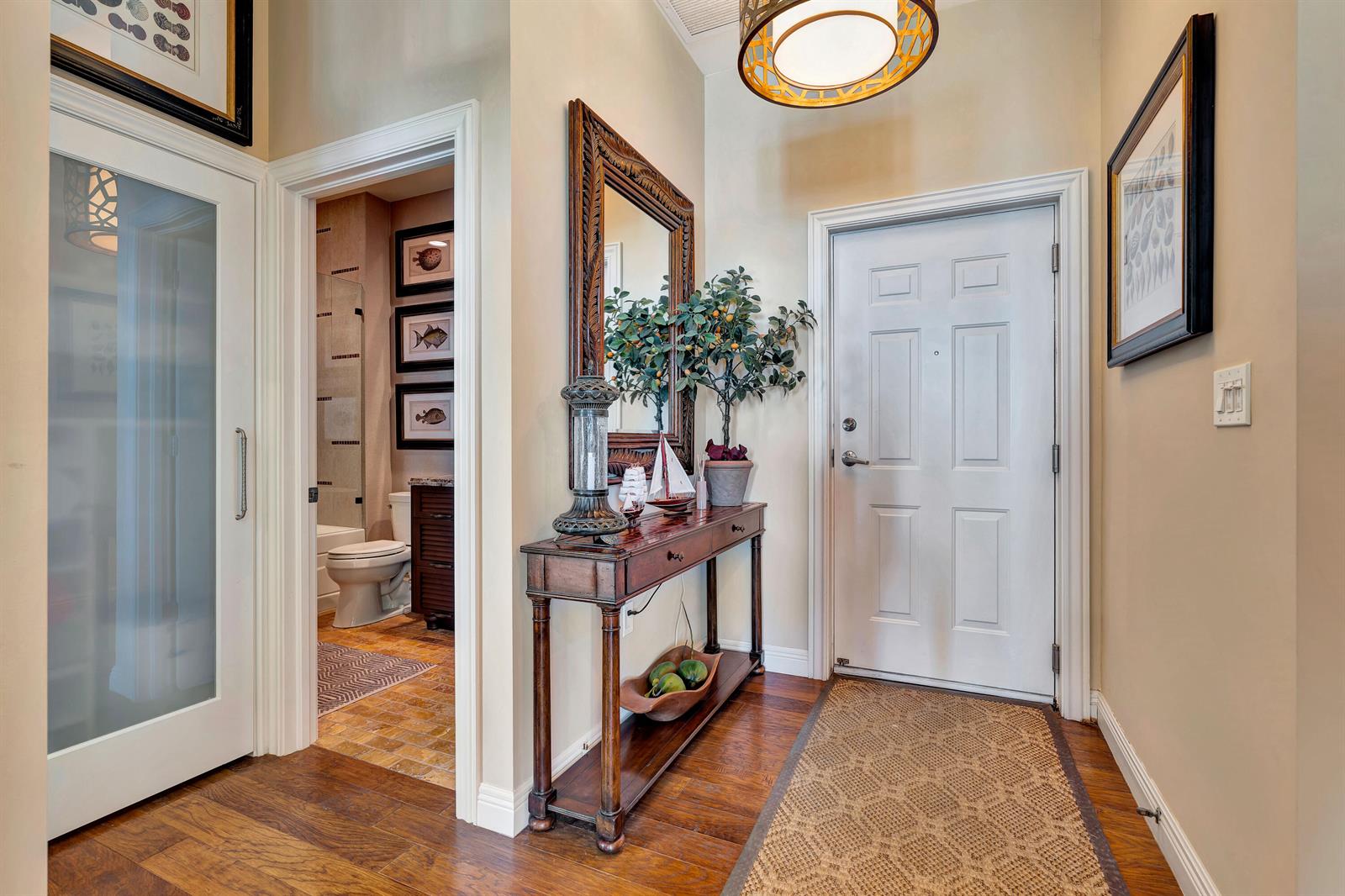 An entryway features a white door, a wooden console table, a mirror, and a bathroom doorway — 2000 S Highway A1a # 603, Jupiter FL 33477, JUPITER, FL