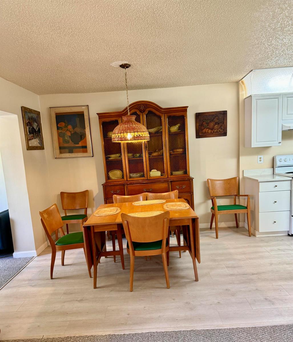 A dining area features a wooden hutch, a drop-leaf table, and chairs with green cushions — 14464 Campanelli Drive, Delray Beach FL 33484, DELRAY BEACH, FL
