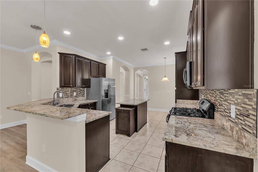 A living room with a stone accent wall, sliding glass doors, and a kitchen island — 17433 NEW CROSS CIRCLE, LITHIA, FL