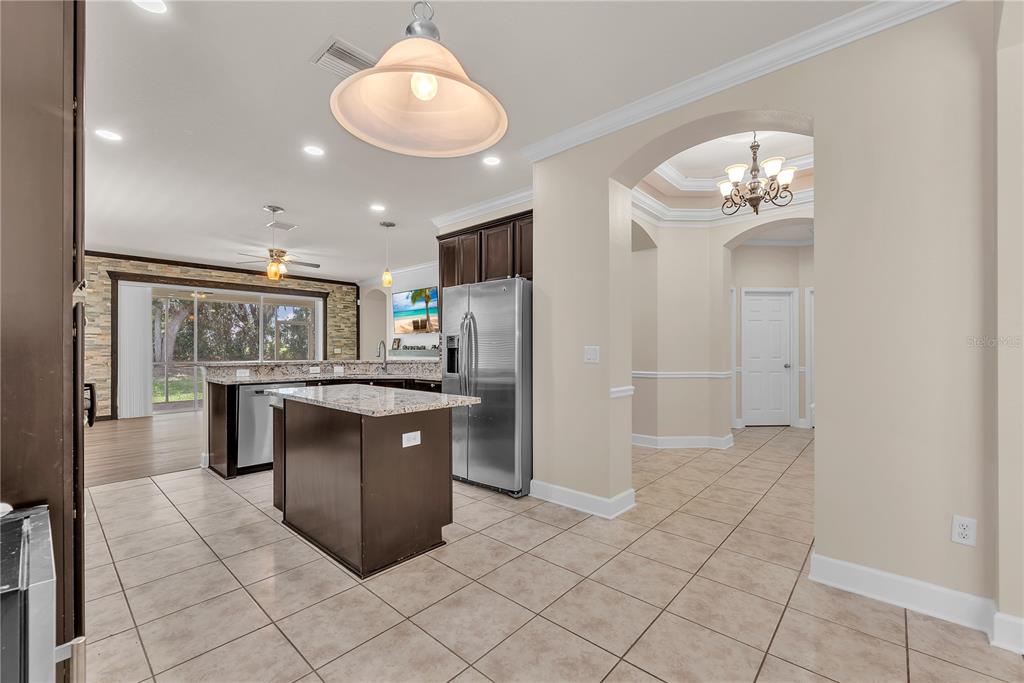 A kitchen and dining area with dark wood cabinets, a stone accent wall, and island — 17433 NEW CROSS CIRCLE, LITHIA, FL
