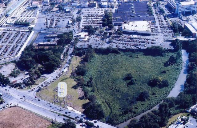 An aerial view shows a vacant, grassy lot bordered by a road, trees, and buildings — PR-29 INT DEGETAU ST., BAYAMON, PR