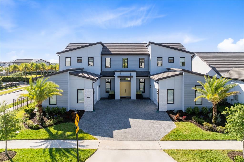 A two-story house with light gray siding, a paver driveway, and two palm trees — 9076 SANTORINI DRIVE, ORLANDO, FL
