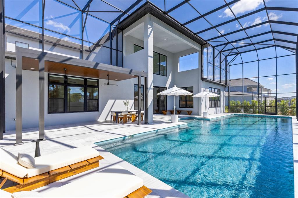 A modern two-story house features a screened-in pool deck with a covered patio area — 9076 SANTORINI DRIVE, ORLANDO, FL
