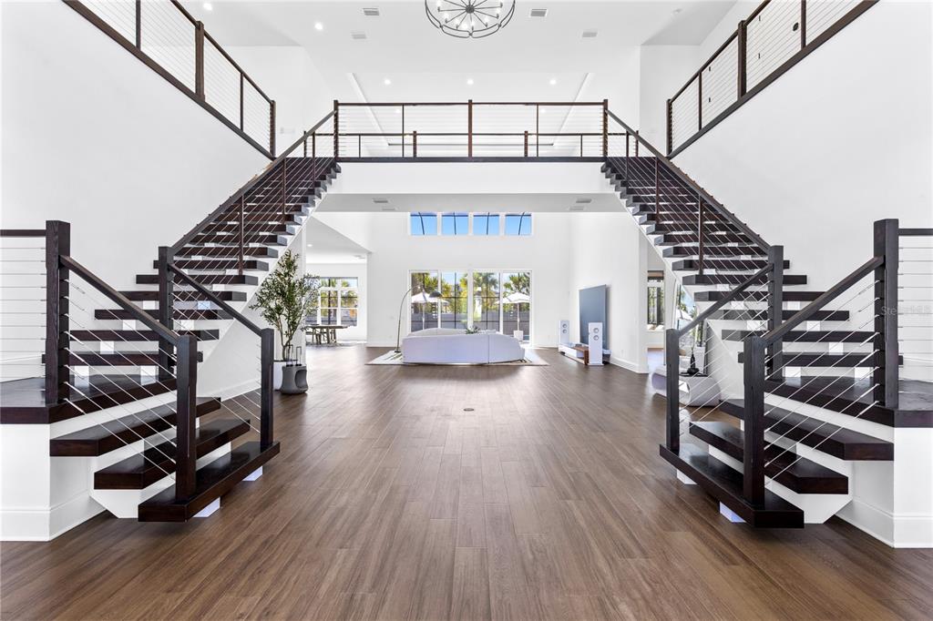 A spacious, modern living area features symmetrical staircases leading to a second-floor landing — 9076 SANTORINI DRIVE, ORLANDO, FL