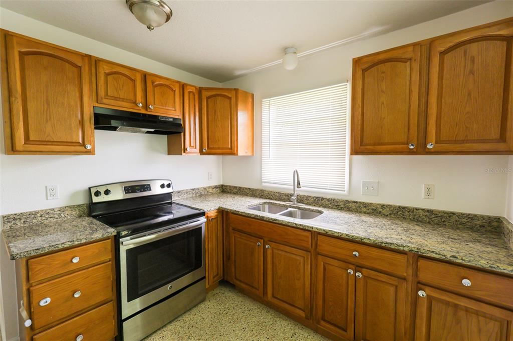 A kitchen with wood cabinets, granite countertops, stainless steel appliances, and a double-basin sink — 8300 57TH STREET N, PINELLAS PARK, FL