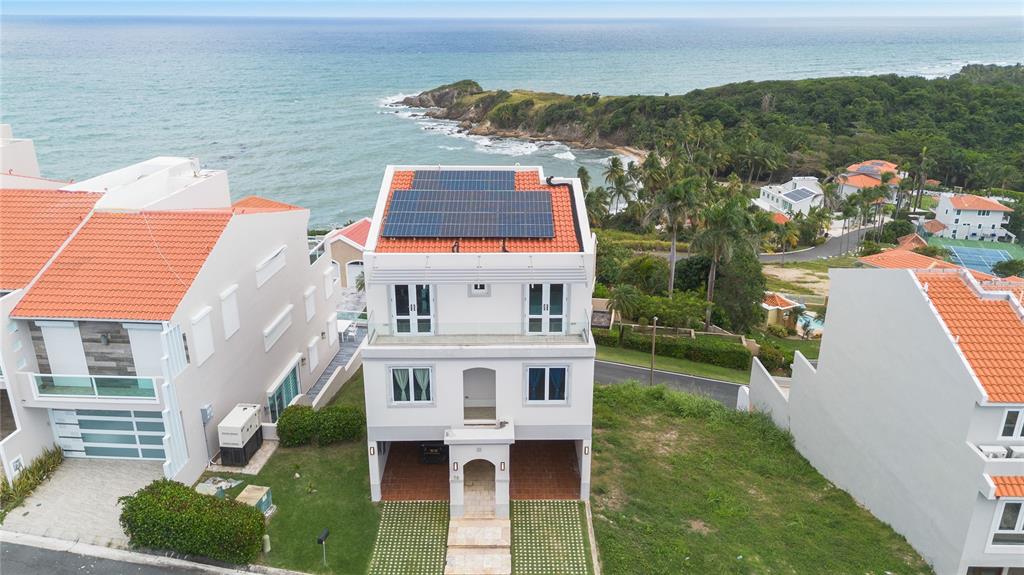 An aerial view shows a three-story house with solar panels on a tiled roof — 1 CALLE UNIT 78, HUMACAO, PR