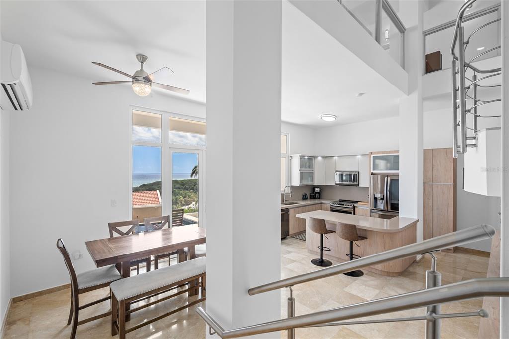 A dining area and kitchen with light wood cabinetry, stone floors, and ocean views — 1 CALLE UNIT 78, HUMACAO, PR