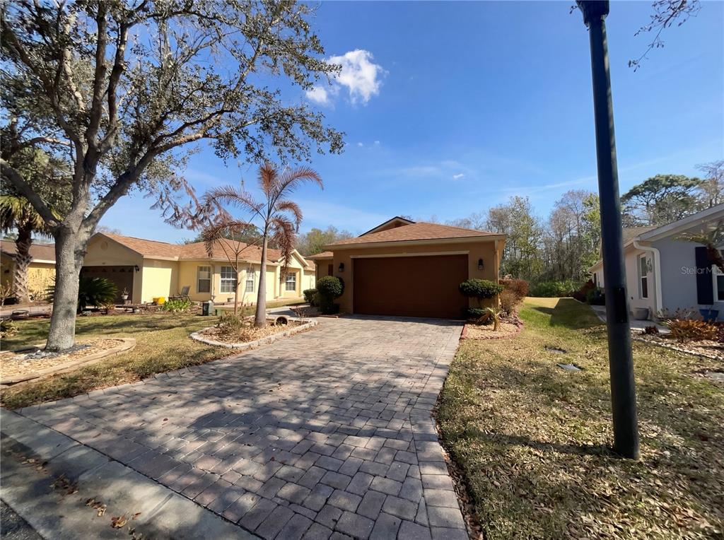 A tan single-story house with a paved driveway and a two-car garage — 396 GRAND CANAL DRIVE, KISSIMMEE, FL
