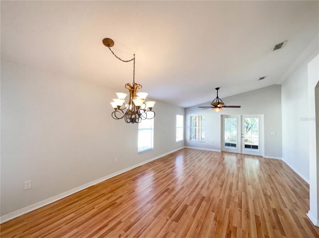 An empty dining room features hardwood floors, a chandelier, a ceiling fan, and glass doors — 396 GRAND CANAL DRIVE, KISSIMMEE, FL