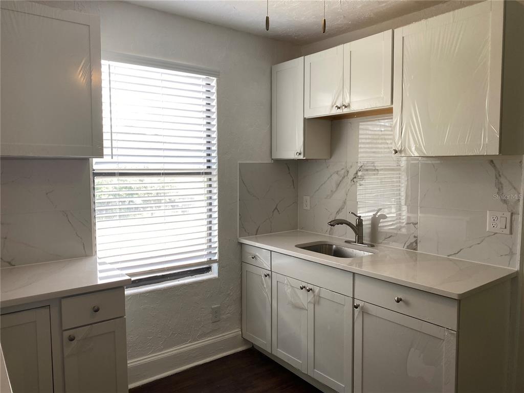 A kitchen features white shaker cabinets, marble-look tile backsplash, and light-colored countertops — 401 COLONIA LANE E UNIT 15, NOKOMIS, FL