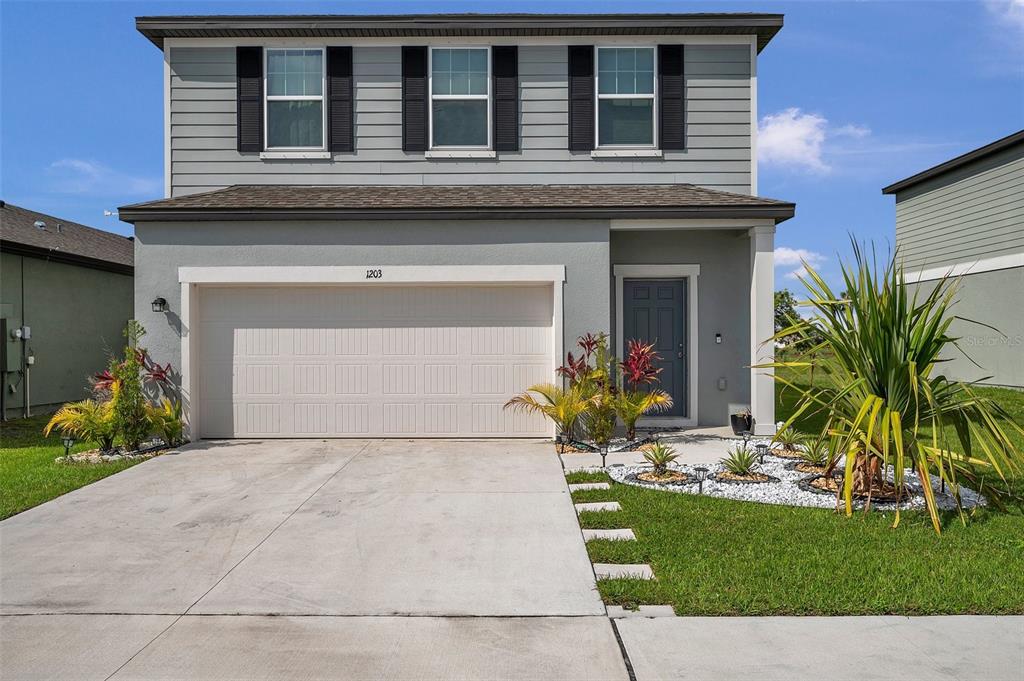 A two-story house with a gray exterior, a two-car garage, and a landscaped front yard — 1203 7TH AVENUE NW, RUSKIN, FL