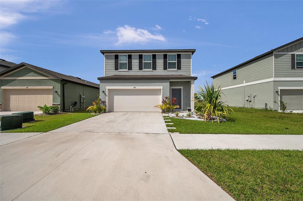 A two-story house with a gray exterior, a two-car garage, and a concrete driveway — 1203 7TH AVENUE NW, RUSKIN, FL