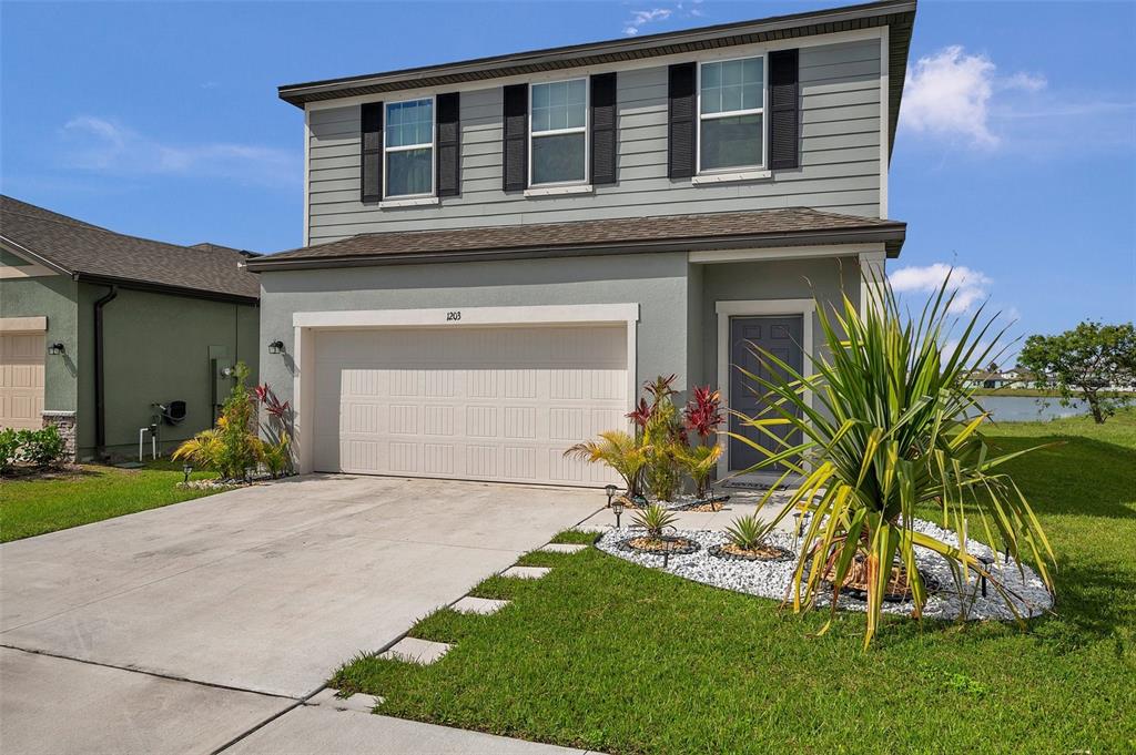 A two-story house with a gray exterior, a two-car garage, and a landscaped front yard — 1203 7TH AVENUE NW, RUSKIN, FL