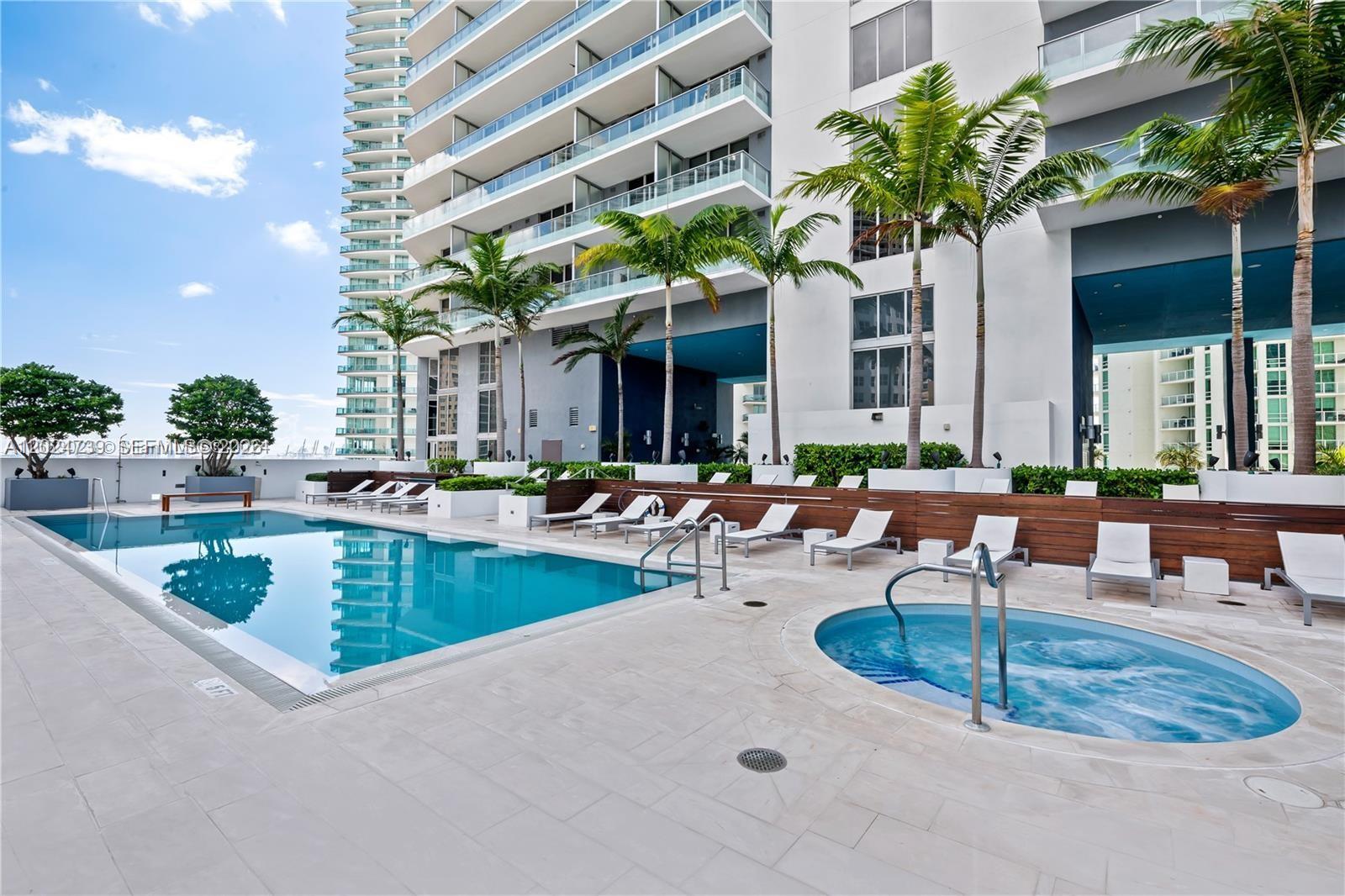 An outdoor swimming pool and hot tub are situated on a patio with lounge chairs — 1300 Brickell Bay Dr # 1007, Miami FL 33131, MIAMI, FL