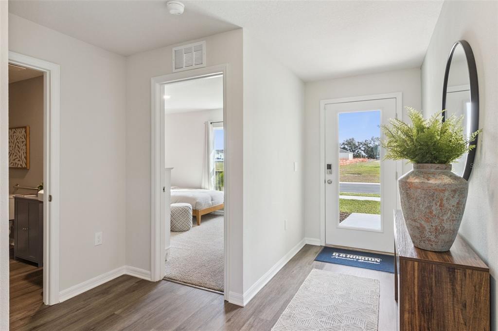 An entryway features wood-look flooring, a front door with a glass panel, and a bedroom view — 2791 ADELINE AVENUE, WINTER HAVEN, FL