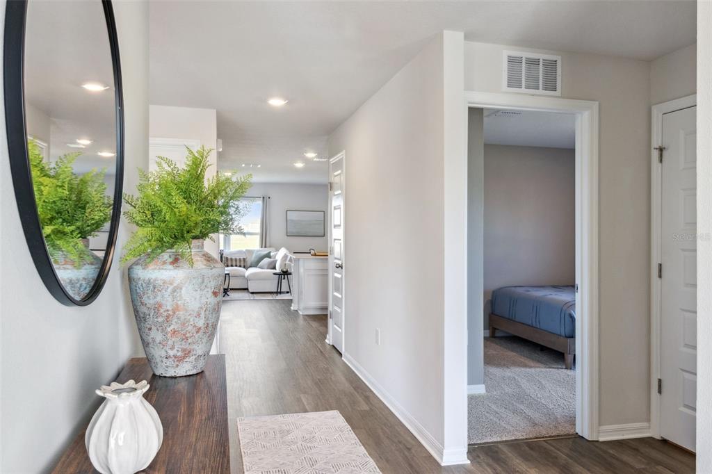 A hallway leads from a foyer with a mirror and plant toward a living area — 2791 ADELINE AVENUE, WINTER HAVEN, FL