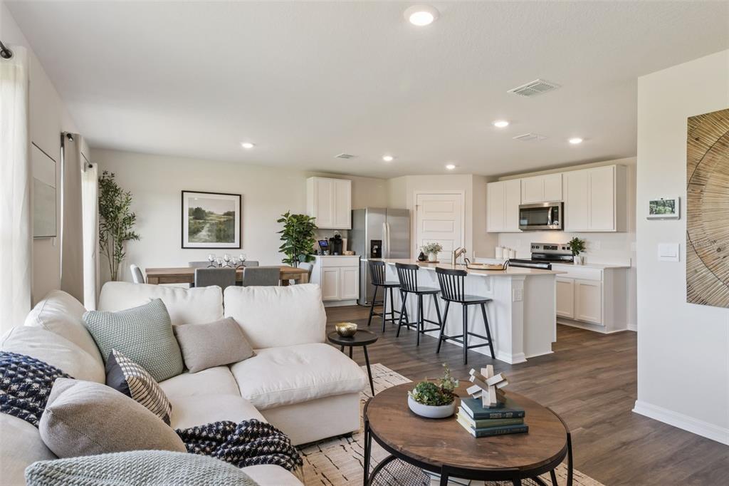An open-concept living room and kitchen feature white cabinetry, a kitchen island, and wood flooring — 2791 ADELINE AVENUE, WINTER HAVEN, FL