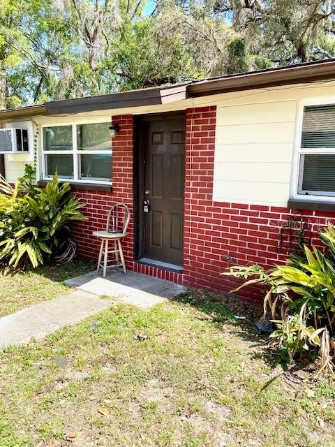 A brick exterior house features a dark brown front door and a small wooden chair — 9418 GREYSTONE ROAD, THONOTOSASSA, FL