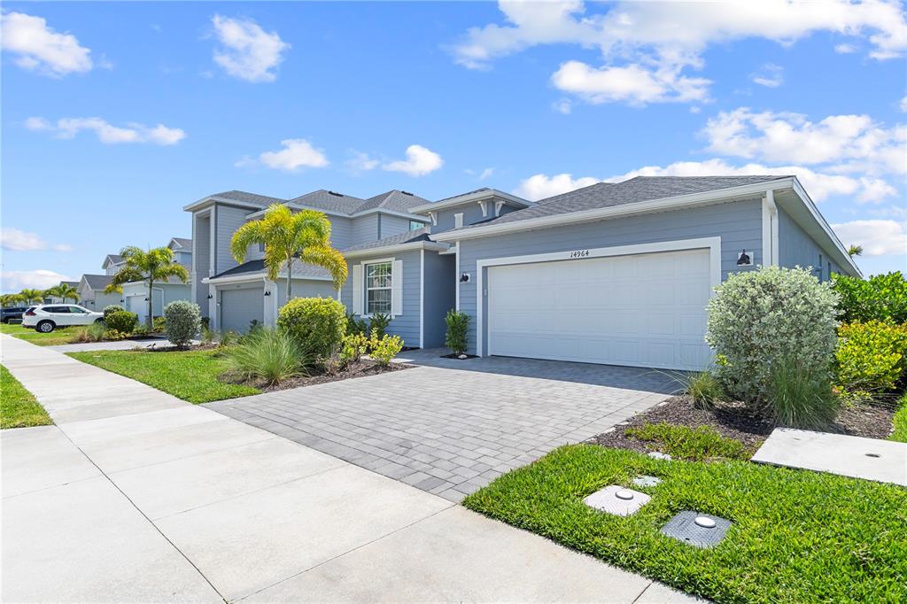 A blue house with a white garage door and a paved driveway under a blue sky — 14964 WHITE PEARL ROAD, PUNTA GORDA, FL
