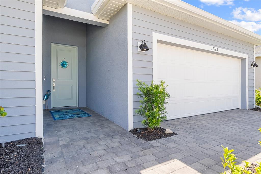 A light blue front door and white garage door are set against gray siding — 14964 WHITE PEARL ROAD, PUNTA GORDA, FL