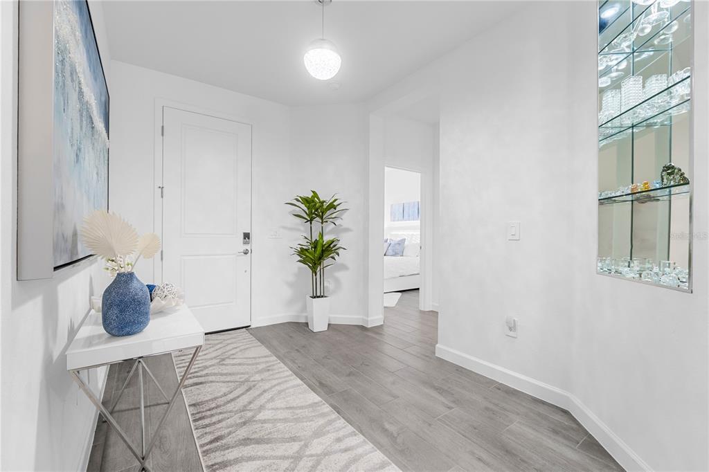 A bright entryway features white walls, gray wood-look tile flooring, a console table, and mirrors — 14964 WHITE PEARL ROAD, PUNTA GORDA, FL