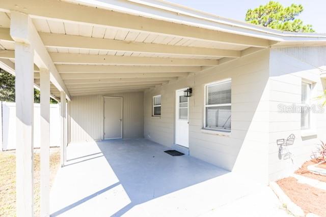 A covered carport area leads to a white door on the side of a house — 4318 BERKLEY DRIVE, TAMPA, FL