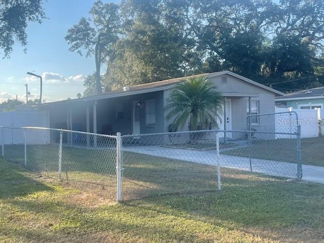 A single-story house with a carport and chain-link fence sits on a grassy lot — 4318 BERKLEY DRIVE, TAMPA, FL