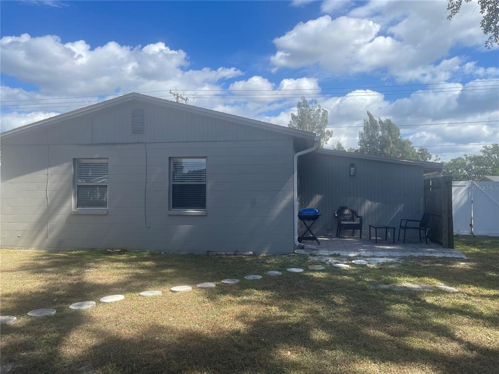 The exterior of a gray house features a small patio area with outdoor furniture — 4318 BERKLEY DRIVE, TAMPA, FL