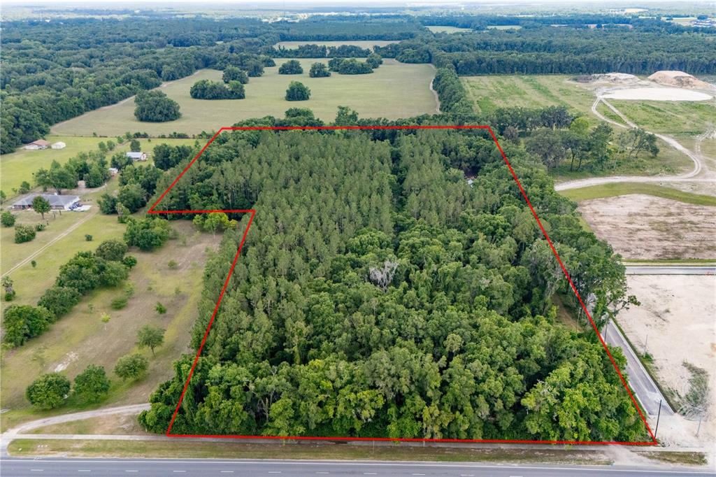 An aerial view shows a wooded lot outlined in red bordering a paved road — 23227 W NEWBERRY ROAD, NEWBERRY, FL