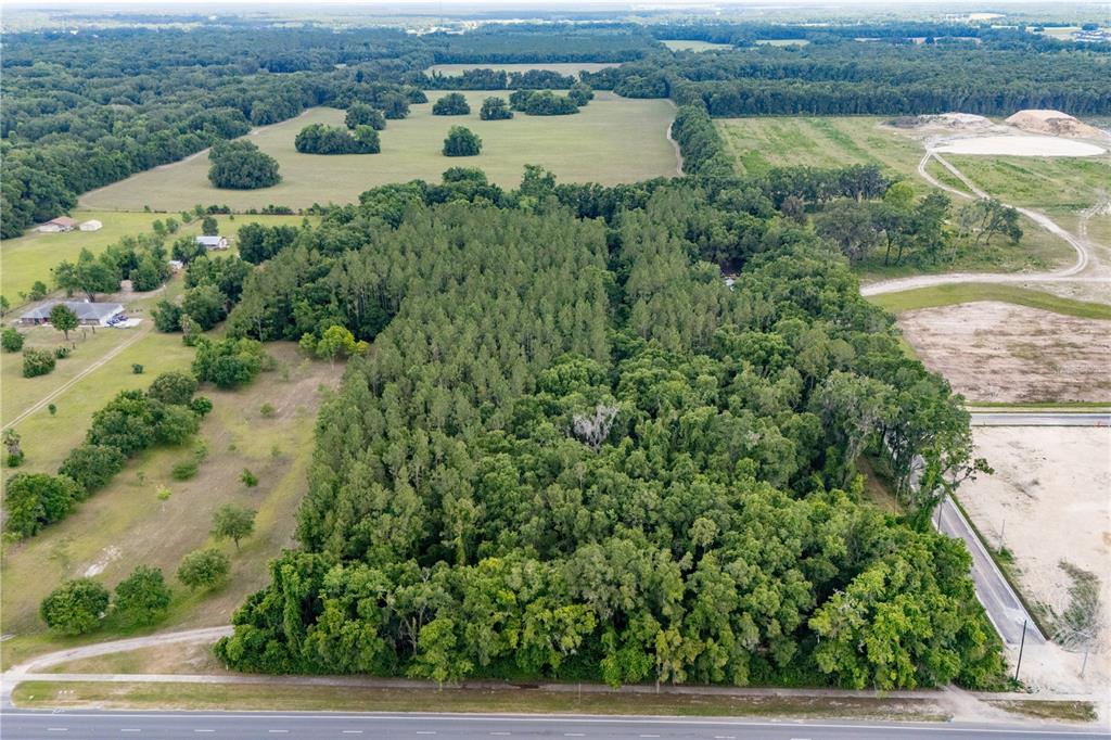 An aerial view shows a large, rectangular wooded lot bordered by a road and fields — 23227 W NEWBERRY ROAD, NEWBERRY, FL