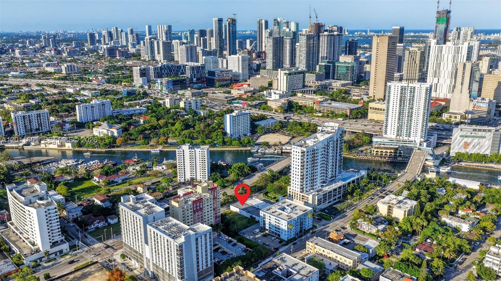 An aerial view shows a city skyline with a red pin marking a specific property — 500 W Flagler St, Miami FL 33130, MIAMI, FL