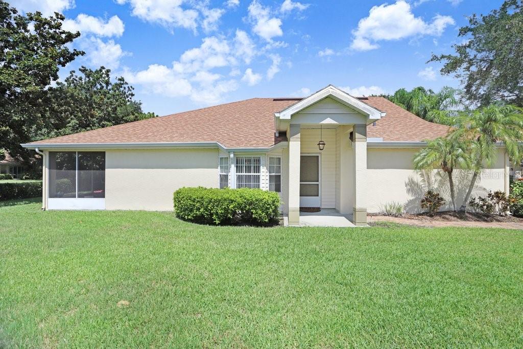 A single-story house with a beige stucco exterior, a covered entryway, and a screened-in porch — 2418 NEW HAVEN CIRCLE UNIT 83, SUN CITY CENTER, FL