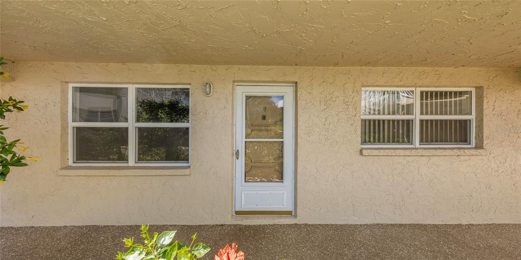 The exterior of a beige stucco building features a front door and two windows — 10032 65TH AVENUE N UNIT 9, ST PETERSBURG, FL