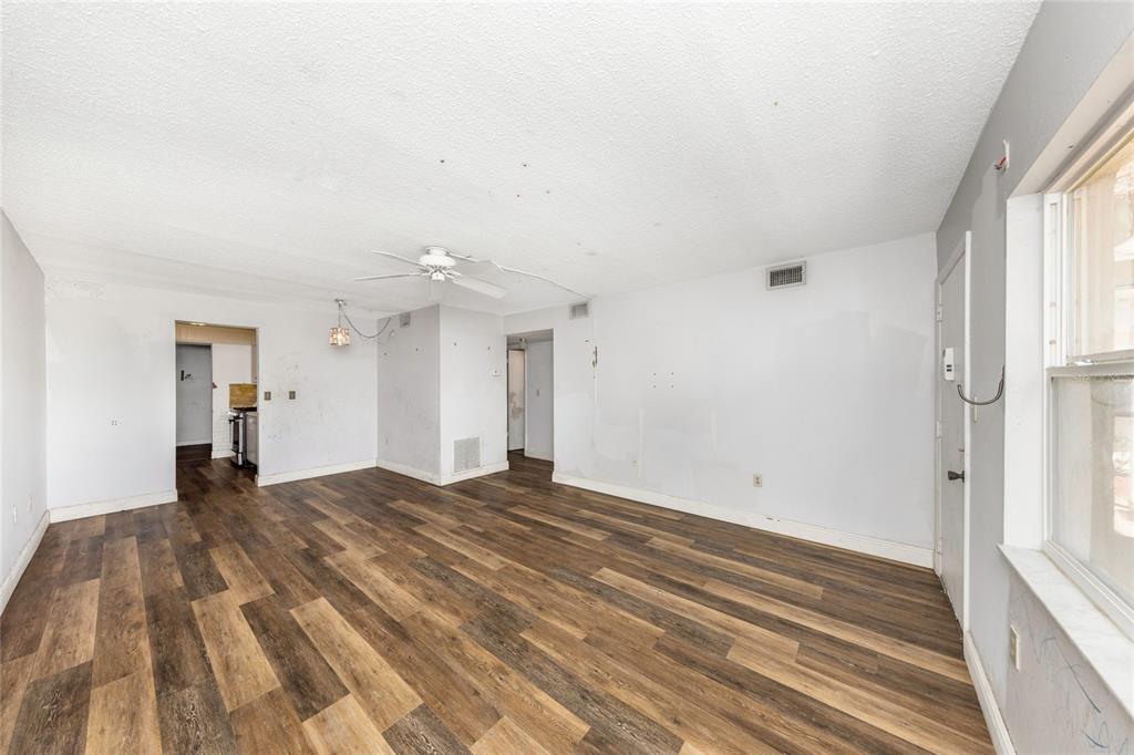 An empty living room features wood-look vinyl flooring, white walls, and a ceiling fan — 10032 65TH AVENUE N UNIT 9, ST PETERSBURG, FL