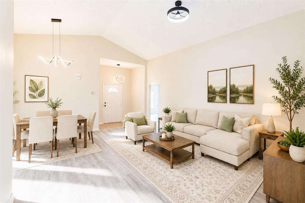 An open-concept living and dining area with vaulted ceilings, light wood flooring, and neutral furniture — 4618 AGUILA PLACE, ORLANDO, FL