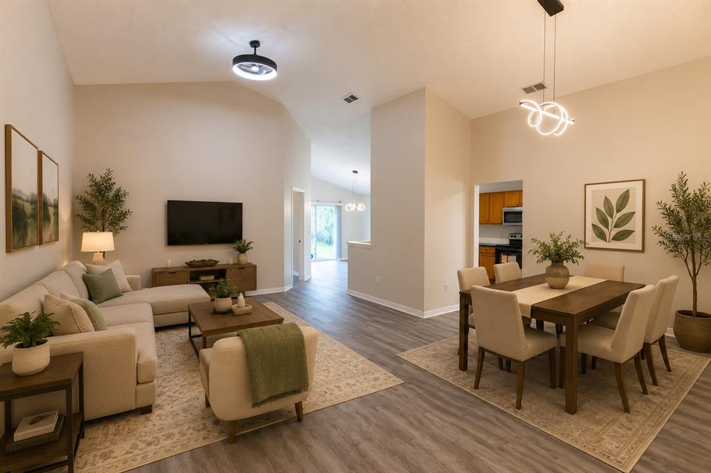 An open-concept living and dining area with vaulted ceilings, light wood flooring, and neutral decor — 4618 AGUILA PLACE, ORLANDO, FL