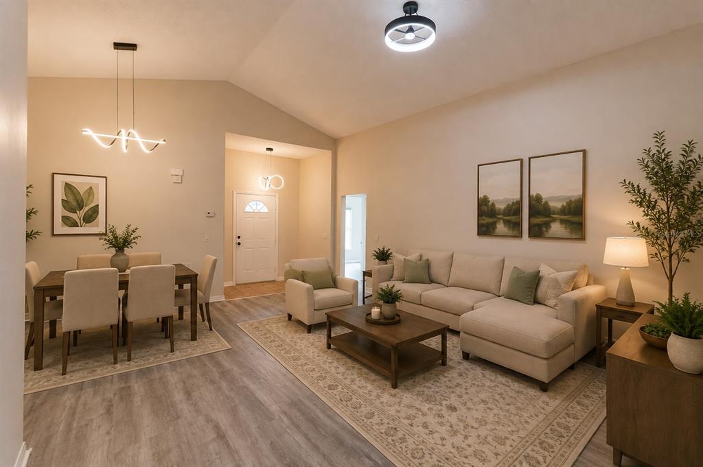 An open-concept living and dining area features light wood-look flooring, neutral furniture, and vaulted ceilings — 4618 AGUILA PLACE, ORLANDO, FL