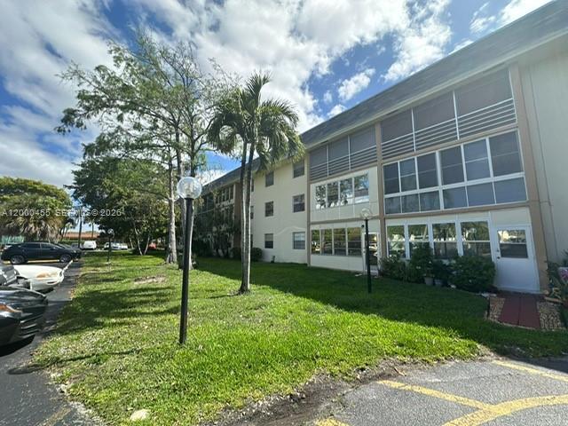 A three-story apartment building features screened balconies and a grassy lawn with palm trees — 4980 E Sabal Palm Blvd # 330, Tamarac FL 33319, TAMARAC, FL