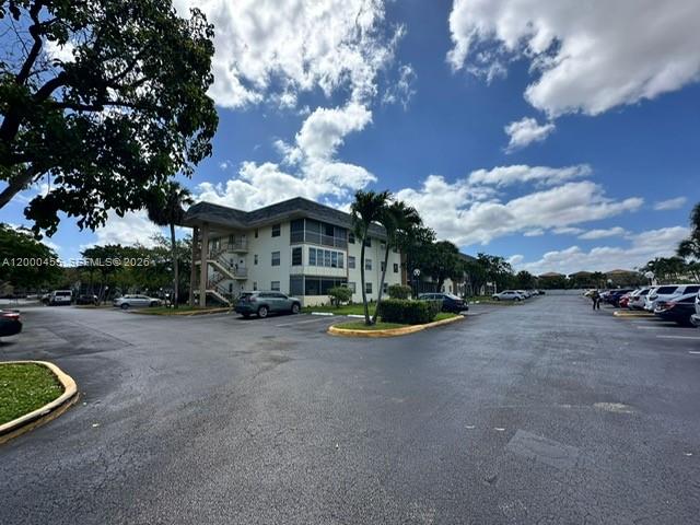 A multi-story apartment building stands behind a large parking lot under a cloudy sky — 4980 E Sabal Palm Blvd # 330, Tamarac FL 33319, TAMARAC, FL